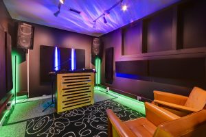 DJ Studio featuring Pioneer CDJs, color changing lights, automated recording, live-streaming capabilities, chairs, and microphones.